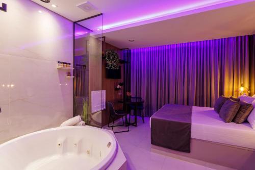 uma casa de banho com banheira e uma cama com iluminação roxa em Medieval Motel SPA em Porto Alegre