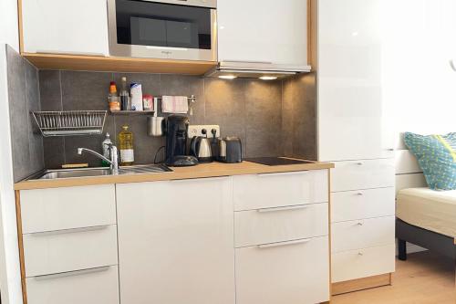 a kitchen with white cabinets and a sink at Coeur Massy M10 Rer BC 600m - Orly20 min in Massy