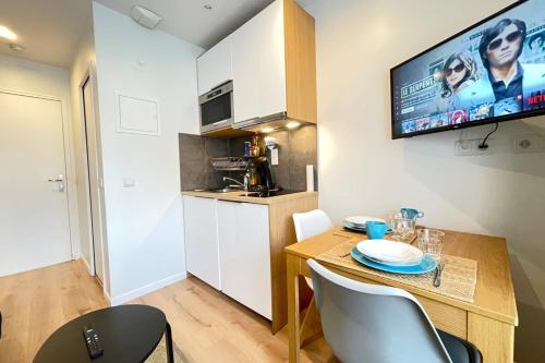 Ce petit appartement comprend une table et une cuisine. dans l'établissement Coeur Massy M7 Rer BC 600m - Orly20 min, à Massy