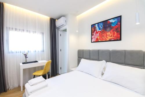 1 dormitorio con 1 cama blanca y 1 silla amarilla en N HOTEL CITY CENTER BY NOSHI en Tirana