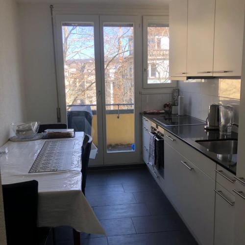 una cucina con armadi bianchi e un tavolo con piano di lavoro di Ein Zimmer in einer 2-Zimmer-Wohnung im Zentrum a Zurigo