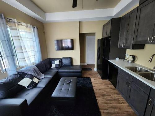 a living room with a black couch and a kitchen at StoneSide Villa in Providenciales