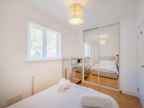 a white room with a bed and a mirror at Seamill Cottage in Seamill