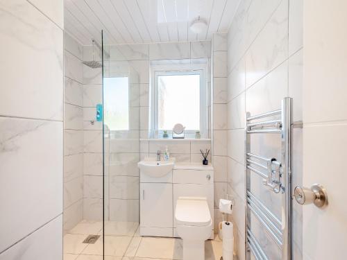 a white bathroom with a toilet and a sink at Seamill Cottage in Seamill