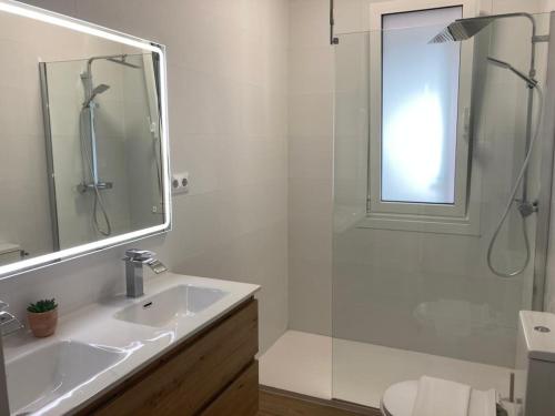 La salle de bains blanche est pourvue d'un lavabo et d'une douche. dans l'établissement Magnífico piso con gran terraza en centro de Vigo, à Vigo