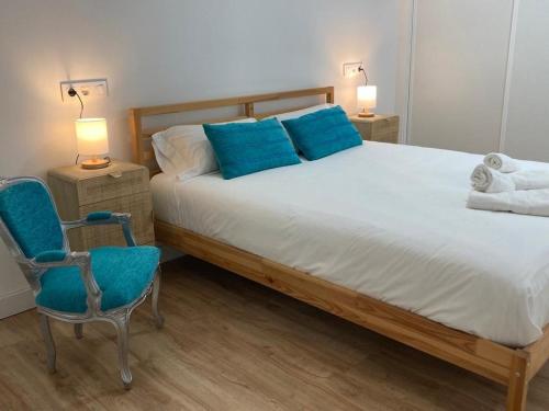 - une chambre avec un grand lit et une chaise bleue dans l'établissement Magnífico piso con gran terraza en centro de Vigo, à Vigo