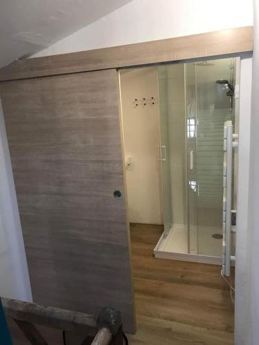 La salle de bains est pourvue d'une douche et d'une porte coulissante en verre. dans l'établissement ancienne maison de tisserande atypique, à Mornac-sur-Seudre