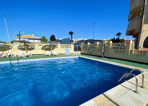 Una piscina con agua azul frente a un edificio. en Apartament na plaży w La Manga, en La Manga del Mar Menor
