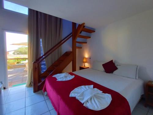a bedroom with a large bed with a red blanket at Pousada Gente Bonita La Mansion in Búzios