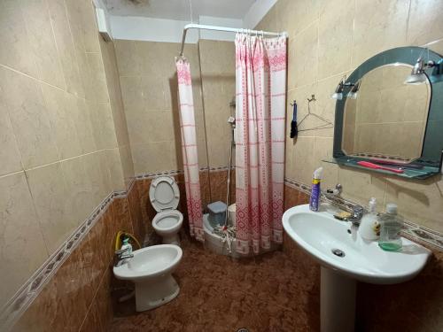 een badkamer met een wastafel, een toilet en een spiegel bij Pallati Kajtazi in Durrës