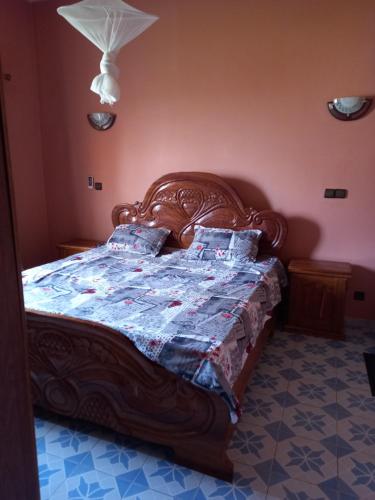 a bedroom with a wooden bed with a quilt on it at Villa meublée climatisée in Ziguinchor