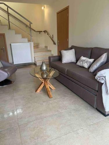 a living room with a brown couch and a table at Villa Artemis Nafplion in Tolo