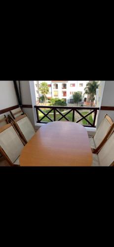 una mesa de madera y sillas en una habitación con ventana en Costa cabo en Martil