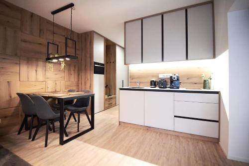 a kitchen with white cabinets and a table and chairs at Apartmány 316 a 317 Vila Zuberec in Zuberec