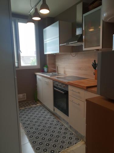 une cuisine avec des armoires blanches et un four à plaques de cuisson dans l'établissement Citytrip Paris, à Bobigny