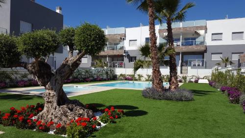 um jardim com palmeiras e flores em frente a um edifício em Marinamed Residential Villa Sea View em Orihuela Costa