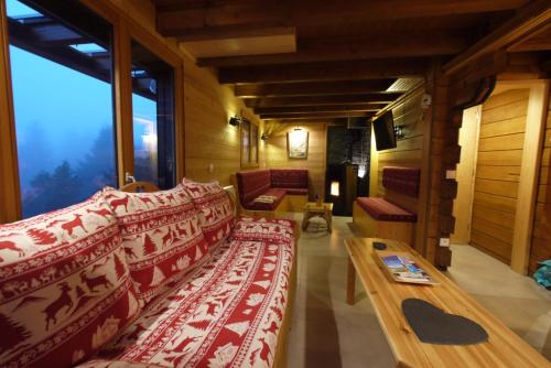 a living room with couches and a table and a large window at Chalet La Trouvaille in Thollon
