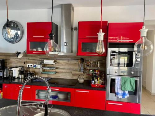 una cucina con armadi rossi e piano di lavoro di kerwatt a Cabourg