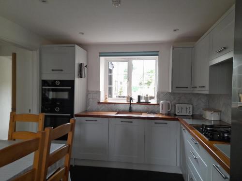 a kitchen with white cabinets and a window at Converted Barn in Bath in Bath