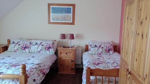 a bedroom with two beds and a night stand with two lamps at Bundoran Guesthouse in Bundoran