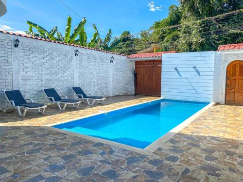 a swimming pool in a backyard with two blue chairs at Alojamiento Familiar Villa Palmeras in Tarapoto