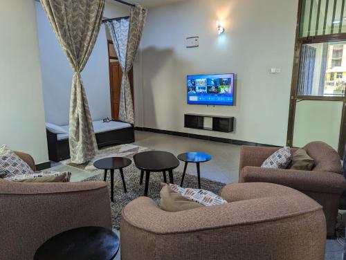 a living room with two chairs and a flat screen tv at Success Apartments - Silver in Mwanza