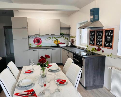 a kitchen with a table with white chairs and a kitchen with at Apartmani LU&LO in Delnice