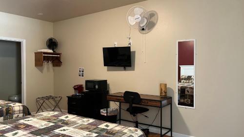 a bedroom with a bed and a desk and a television at Denali Rainbow Village RV Park and Motel in McKinley Park