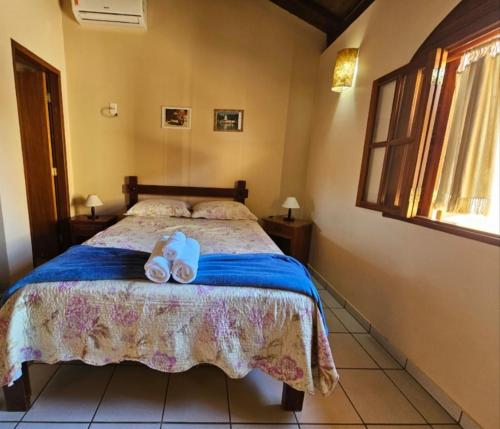 a bedroom with a bed with a pair of shoes on it at Pousada do Abacateiro in Pirenópolis
