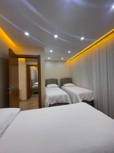 um quarto de hotel com três camas com lençóis brancos em شقه حديثه بمساحه كبيره 13 em Istambul