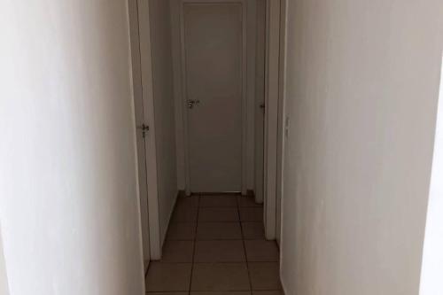 a hallway with two white doors and a tile floor at Apto 2Q Wifi Garagem Shopping in Taubaté