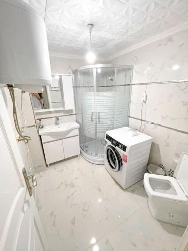 La salle de bains blanche est pourvue d'un lave-linge et de toilettes. dans l'établissement شقه حديثه 2023 مناسبه للعائلات, à Istanbul