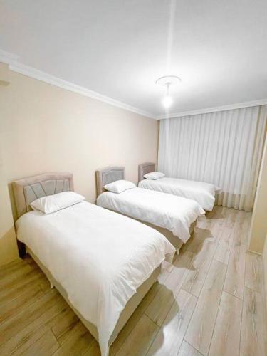 3 lits dans une chambre dotée de murs blancs et de parquet dans l'établissement شقه حديثه 2023 مناسبه للعائلات, à Istanbul