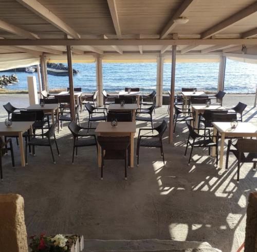 Sunset Sea View في Elíka: مطعم بالطاولات والكراسي والمحيط