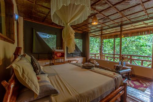 a bedroom with a bed in a room with windows at Rushaga Gorilla Lodge in Bugambira