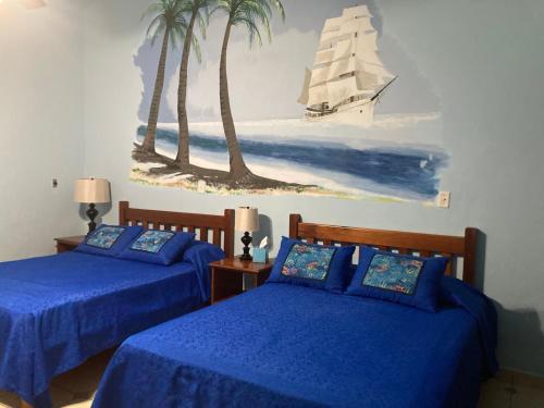 1 dormitorio con 2 camas y una pintura de un velero en Las Lajas Beach Resort, en Las Lajas