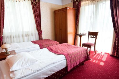 una habitación de hotel con 2 camas y una silla en Hotel Korona en Sandomierz