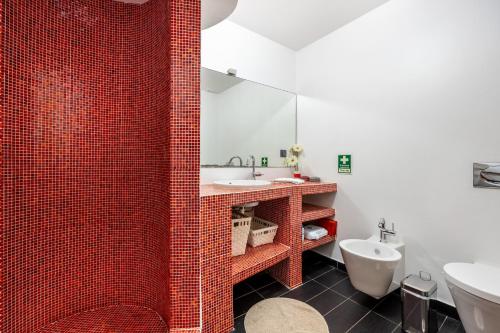 baño de azulejos rojos con lavabo y aseo en Villa Jimmy, en Armação de Pêra