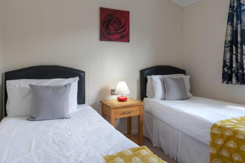 a bedroom with two beds and a table with a lamp at 56 Meadow View in Woolacombe