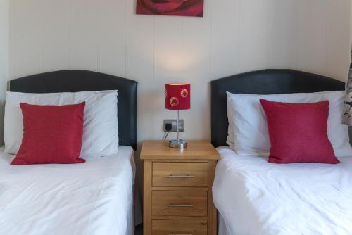 two beds with red pillows sitting next to each other at 56 Meadow View in Woolacombe