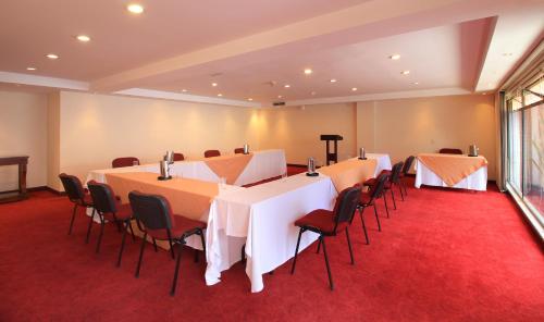 a conference room with tables and chairs on a red carpet at Hotel Windsor House Inn By GEH Suites in Bogotá