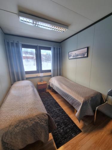 een slaapkamer met 2 bedden en een raam bij Storgalten gjestehus in Nord-Lenangen