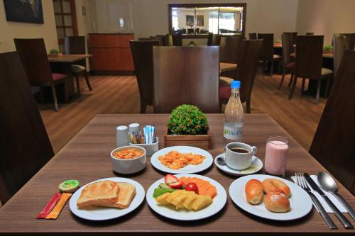 a table with plates of breakfast food on it at Hotel Windsor House Inn By GEH Suites in Bogotá