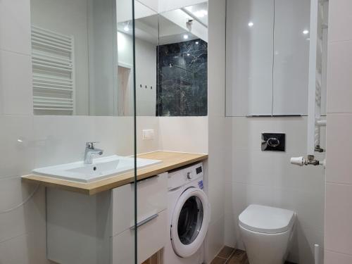 a white bathroom with a washing machine and a sink at Victoria Garden in Tarnowo Podgórne