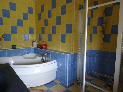 La salle de bains bleue et jaune est pourvue d'une baignoire et d'une douche. dans l'établissement Maison au cœur de la Drôme, à Rochebaudin