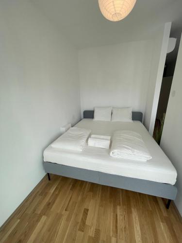 een bed in een kamer met witte muren en houten vloeren bij Swan Stay Property 17 in Wenen