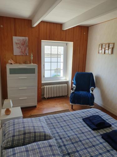 une chambre avec un lit et une chaise bleue dans l'établissement Gîte Au café des marguerites, à Plounévez-Lochrist