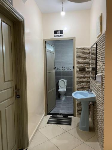 a bathroom with a toilet and a sink at hôtel Bahnini in Dakhla