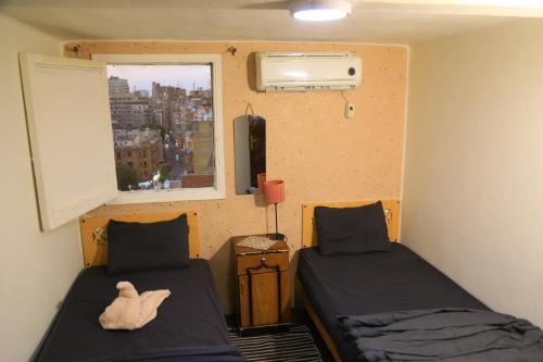 una piccola stanza con due letti e una finestra di Castle Hotel a Il Cairo