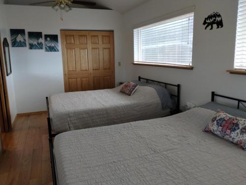 a bedroom with two beds and two windows at Sky Harbor Cabin - Homer Seaplane Base in Homer